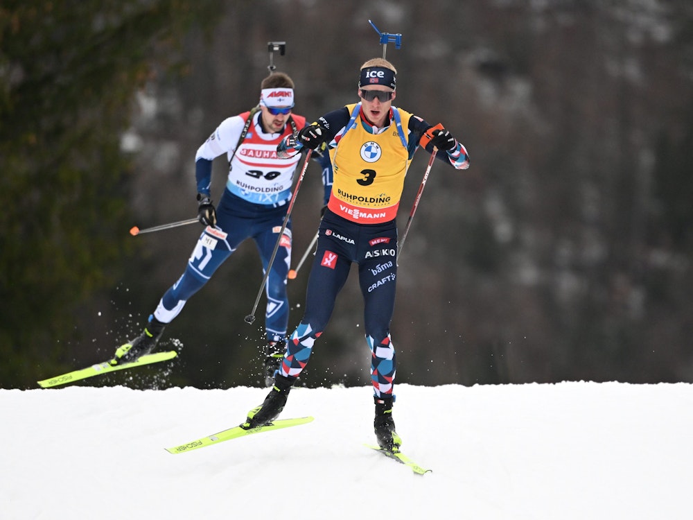 Die Biathleten Johannes Thingnes Bö aus Norwegen (r) und Olli Hiidensalo aus Finnland (l) in Aktion in der Loipe.