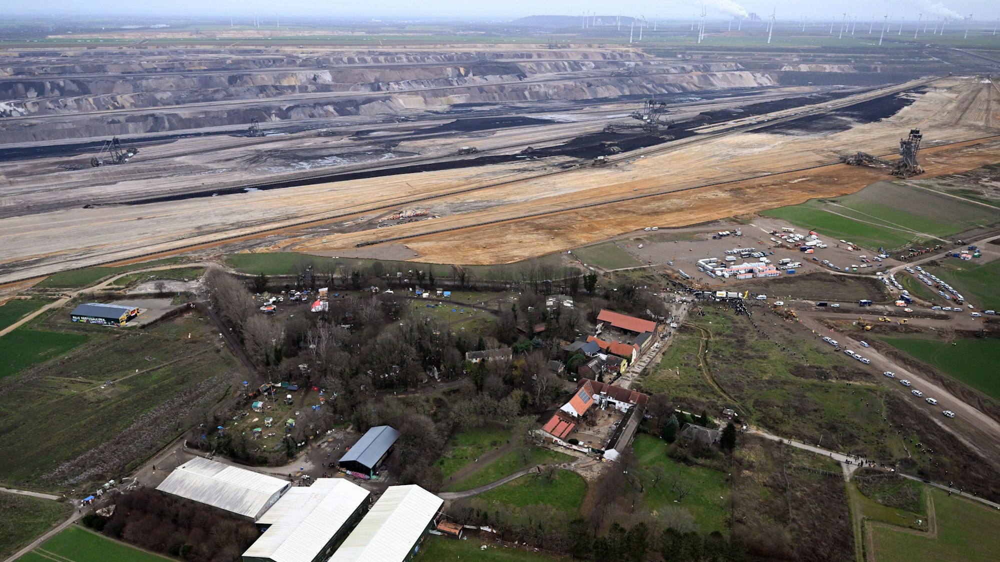 Eine Luftaufnahme des Dorfes Lützerath. Im Hintergrund sind die Ausmaße des Braunkohletagebaus zu sehen.