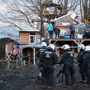 Polizisten stehen bei der Räumung von Lützerath vor Bretterhütten.