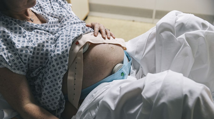 Eine unkenntliche, schwangere Frau liegt in einem Krankenhausbett.