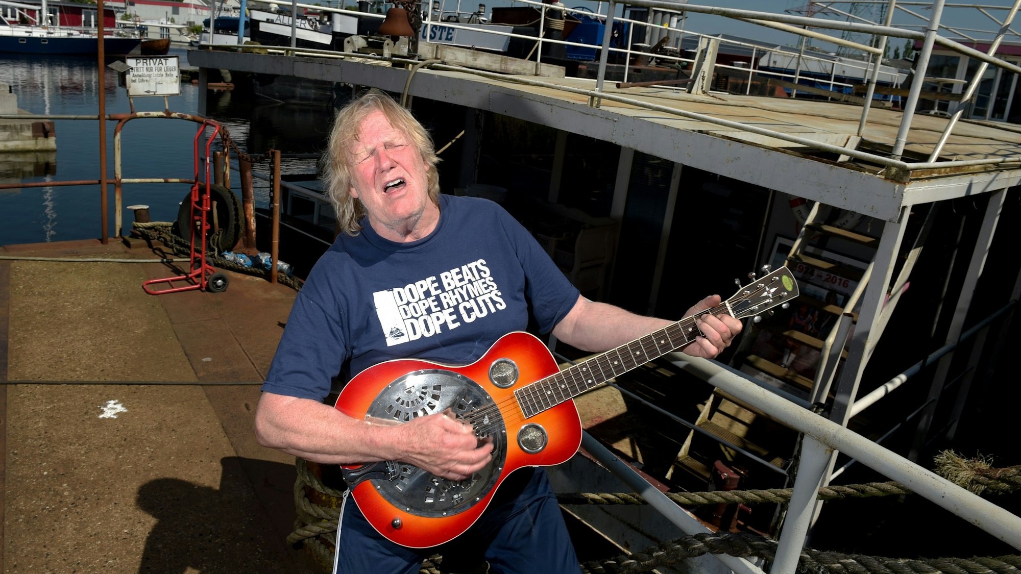 Der Musiker Gunter Gabriel spielt im Hafen vor seinem Hausboot Gitarre.