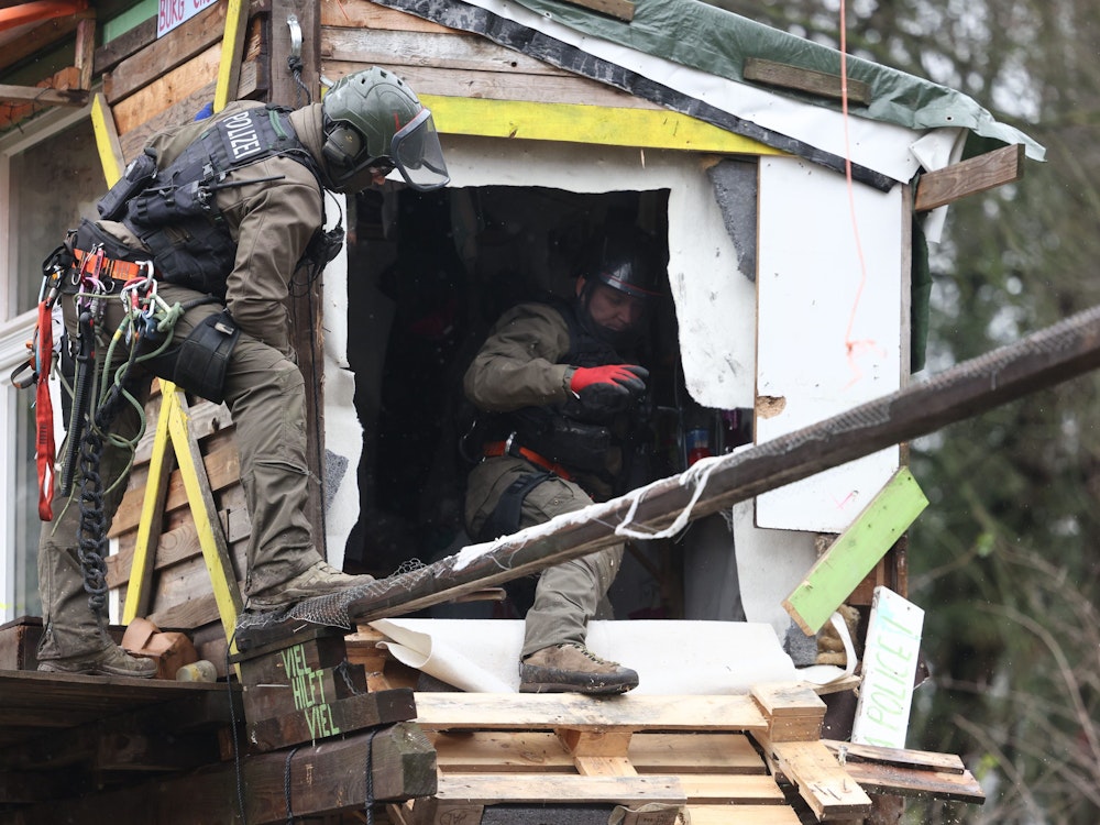 Polizisten untersuchen am zweiten Tag der Räumung im von Klimaaktivisten besetzten Braunkohleort Lützerath ein verlassenes Holzhaus.