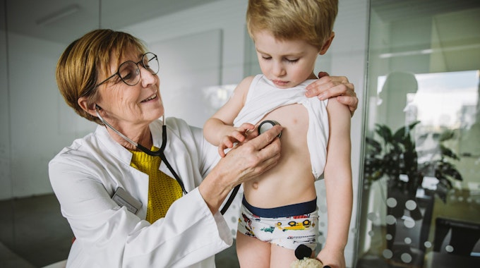 Eine Kinderärztin untersucht einen kleinen Jungen mit dem Stethoskop.