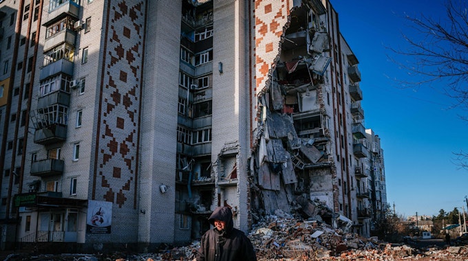 TOPSHOT - A man walks by a destroyed residential building in the city of Lyman, Donetsk region on January 4, 2023, amid the Russian invasion of Ukraine. (Photo by Dimitar DILKOFF / AFP)