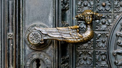 Das Bild zeigt einen bronzenen Türgriff in Form eines Engels mit Lockenkopf am Kölner Dom.&nbsp;