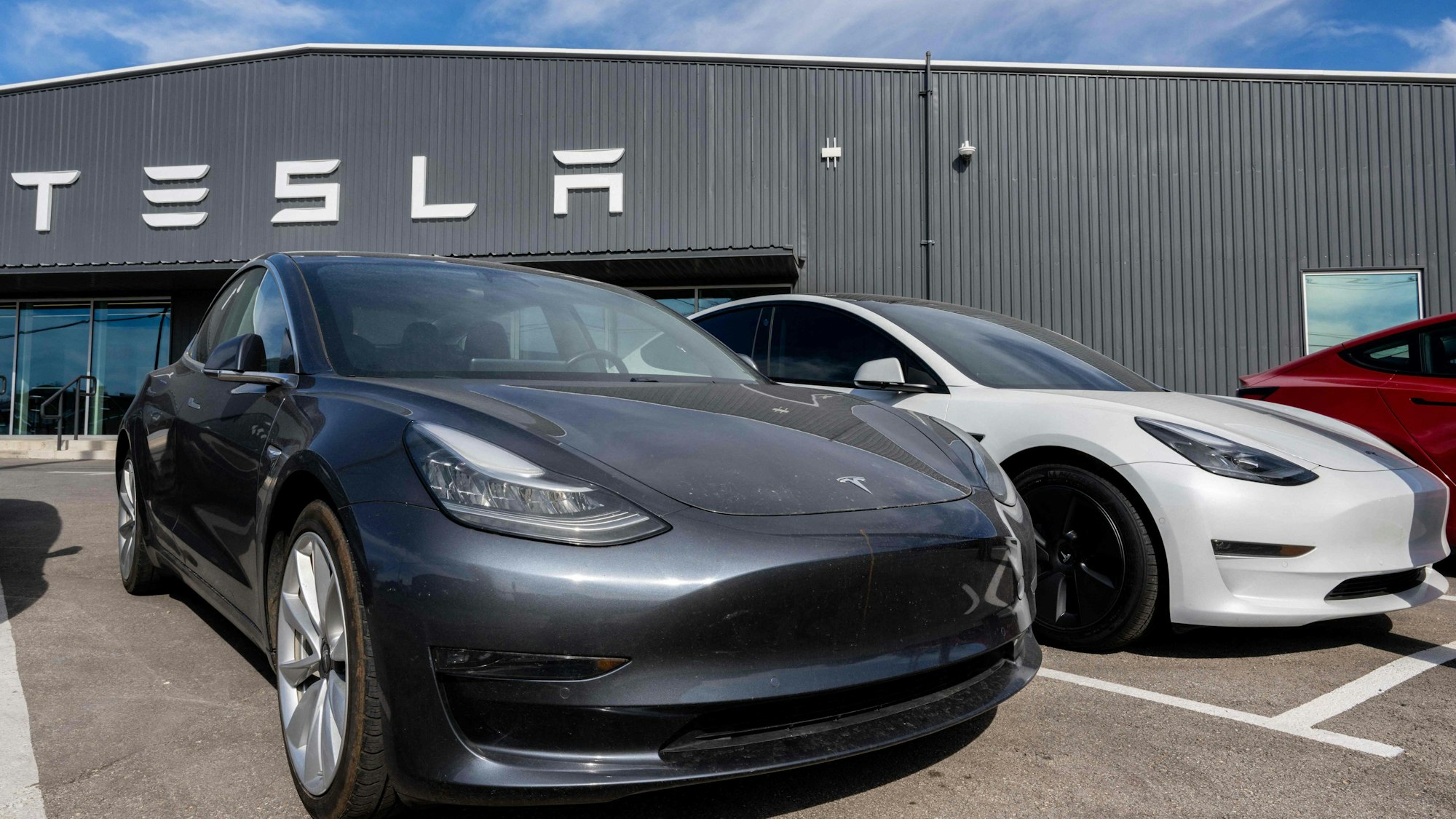 Autos von Tesla stehen vor einem Autohaus von Tesla.