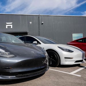 Autos von Tesla stehen vor einem Autohaus von Tesla.