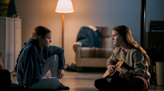 Die Zwillinge Tegan and Sara sitzen auf dem Boden mit einer Gitarre