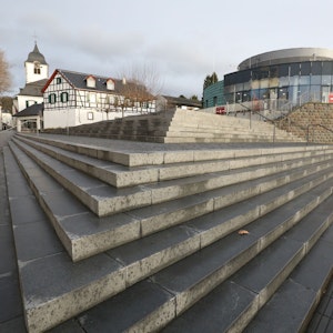 Graue Treppenstufen führen zu dem Rundbau, der bis zum 31. Dezember das Sea Life beherbergte. Links im Hintergrund ist der Turm der Pfarrkirche St. Remigius zu sehen.