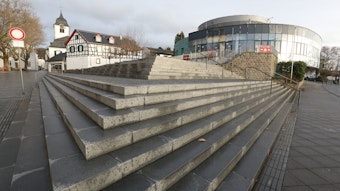 Eine Treppenanlage führt auf das runde Gebäude zu, das bis Ende Dezember das Sealife-Aquarium beherbergte. Im Hintergrund links ist der Turm der Pfarrkirche St-Remigius zu sehen..