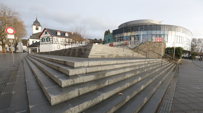Eine Treppenanlage führt auf das runde Gebäude zu, das bis Ende Dezember das Sealife-Aquarium beherbergte. Im Hintergrund links ist der Turm der Pfarrkirche St-Remigius zu sehen..