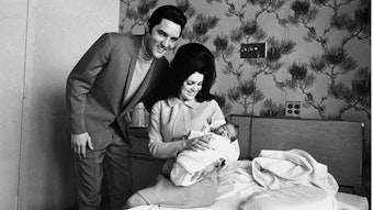 Lisa Marie Presley liegt auf dem Schoß ihrer Mutter Priscilla neben ihrem Vater Elvis Presley.