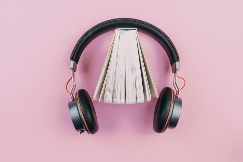 Buch und Kopfhörer auf pinkem Hintergrund