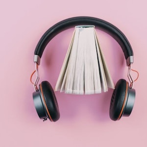 Buch und Kopfhörer auf pinkem Hintergrund