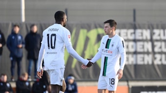 Marcus Thuram (l.) und Stefan Lainer (r.) von Borussia Mönchengladbach beim Testspiel gegen Arminia Bielefeld am 11. Januar 2023 klatschen beim Wechsel ab. Thuram ist dabei von hinten zu sehen, Lainer in einer seitlichen Frontansicht.