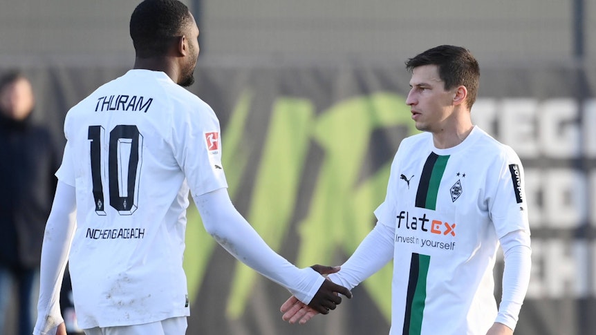 Marcus Thuram (l.) und Stefan Lainer (r.) von Borussia Mönchengladbach beim Testspiel gegen Arminia Bielefeld am 11. Januar 2023 klatschen beim Wechsel ab. Thuram ist dabei von hinten zu sehen, Lainer in einer seitlichen Frontansicht.