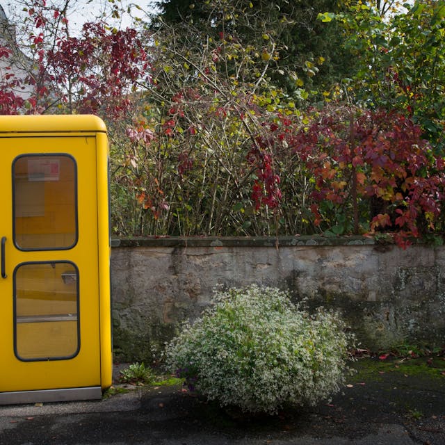 Eine gelbe Telefonzelle steht am Rande einer Straße. 