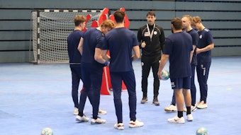 Mehrere Handballspieler des VfL Gummersbach stehen mit ihrem Co-Trainer im Kreis.