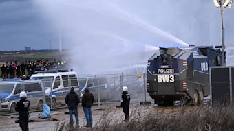 Lützerath: Die Polizei fährt mit einem Wasserwerfer bei einer Demonstration an Klimaaktivisten vorbei.
