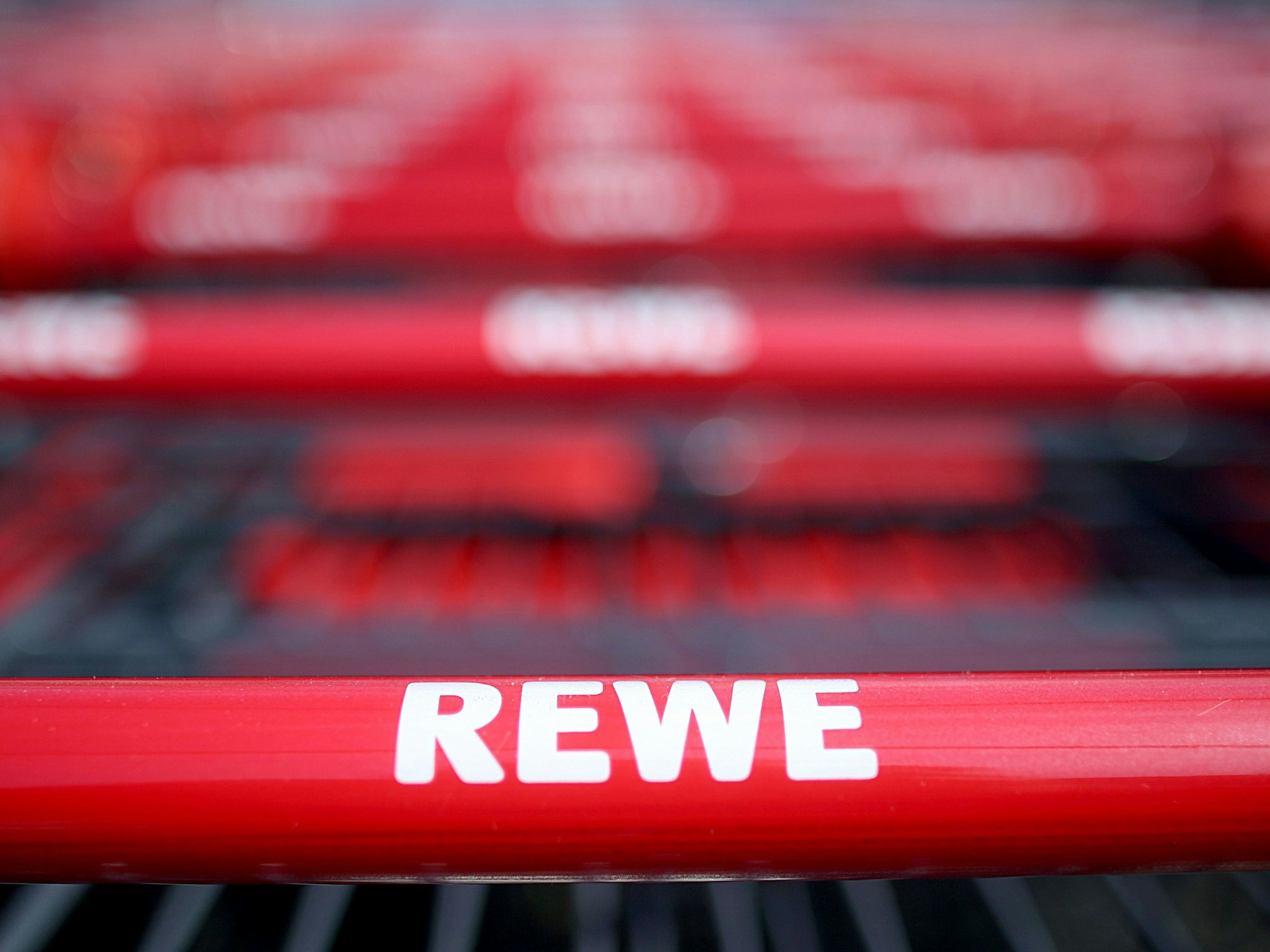 Einkaufswagen stehen vor einem Rewe-Supermarkt in Köln.