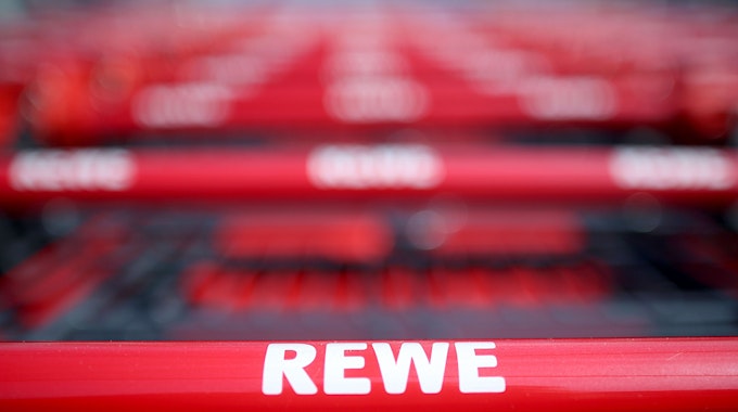 Einkaufswagen stehen vor einem Rewe-Supermarkt in Köln.