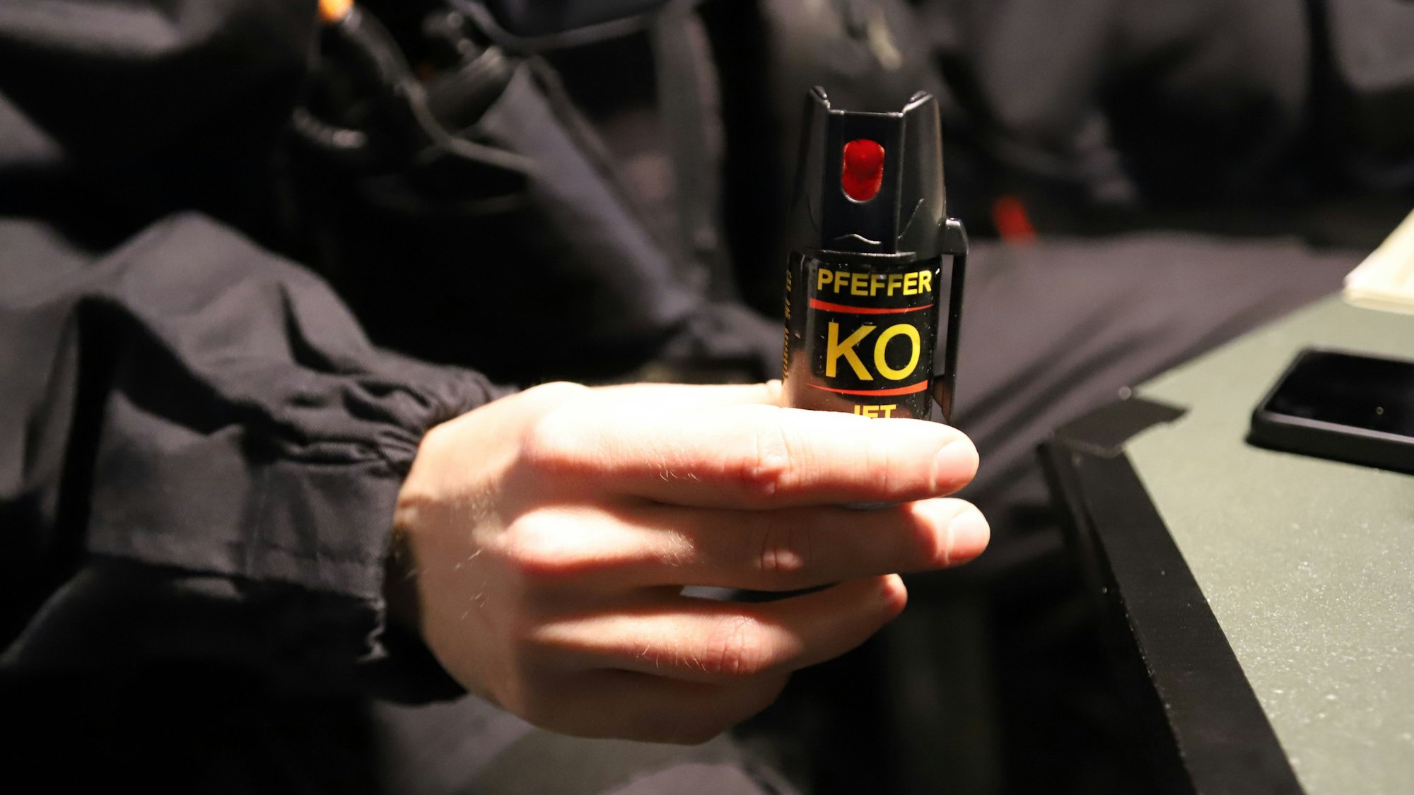 Eine Hand hält eine kleine Sprühflasche mit der Aufschrift Pfeffer-KO in die Kamera.