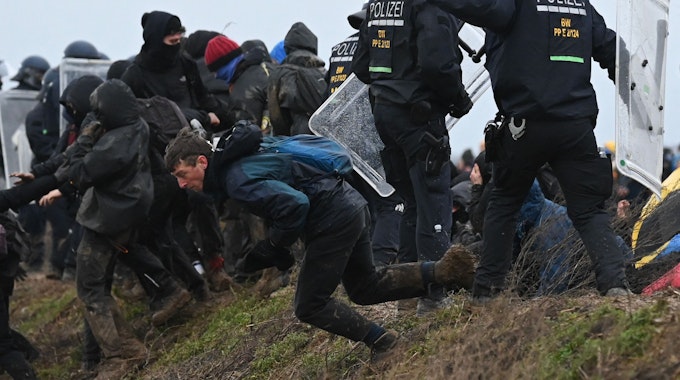 Klimaschutzaktivisten durchbrechen bei einer Demonstration gegen den Abriss des Braunkohledorfs Lützerath eine Polizeiabsperrung. Laut offiziellen Angaben wurden während der Räumung mehr als 100 Polizisten verletzt.
