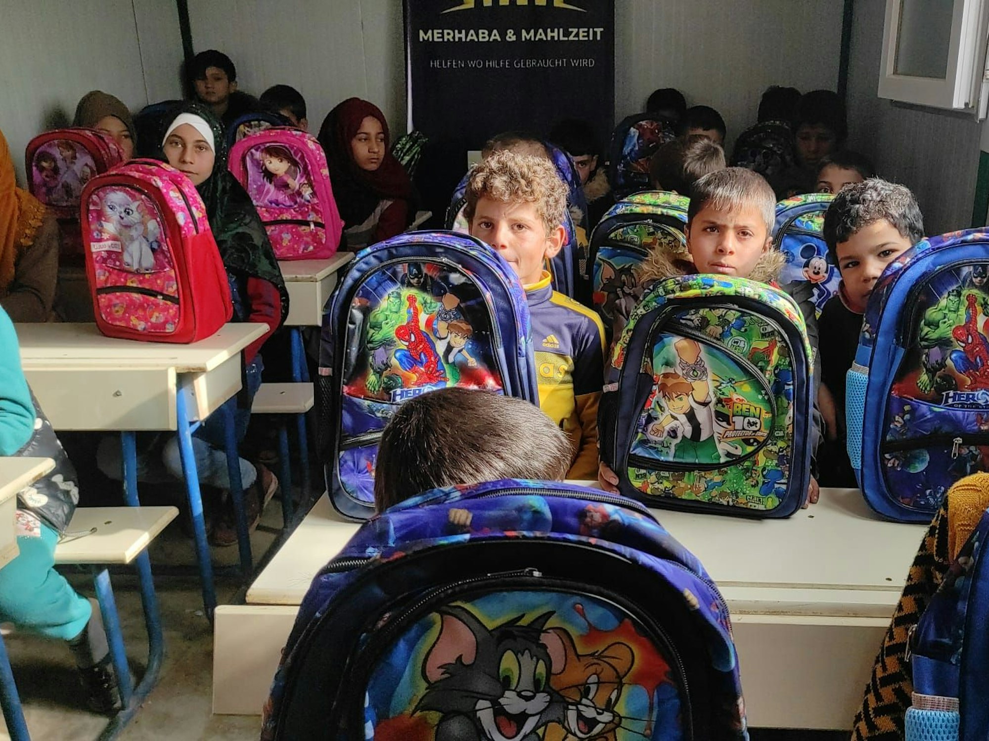 Kinder mit Schulranzen sitzen in einer Klasse.