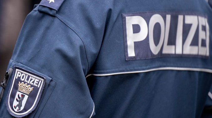 Die Aufschrift Polizei und der Wappen von Berlin auf der Uniform eines Polizeibeamten