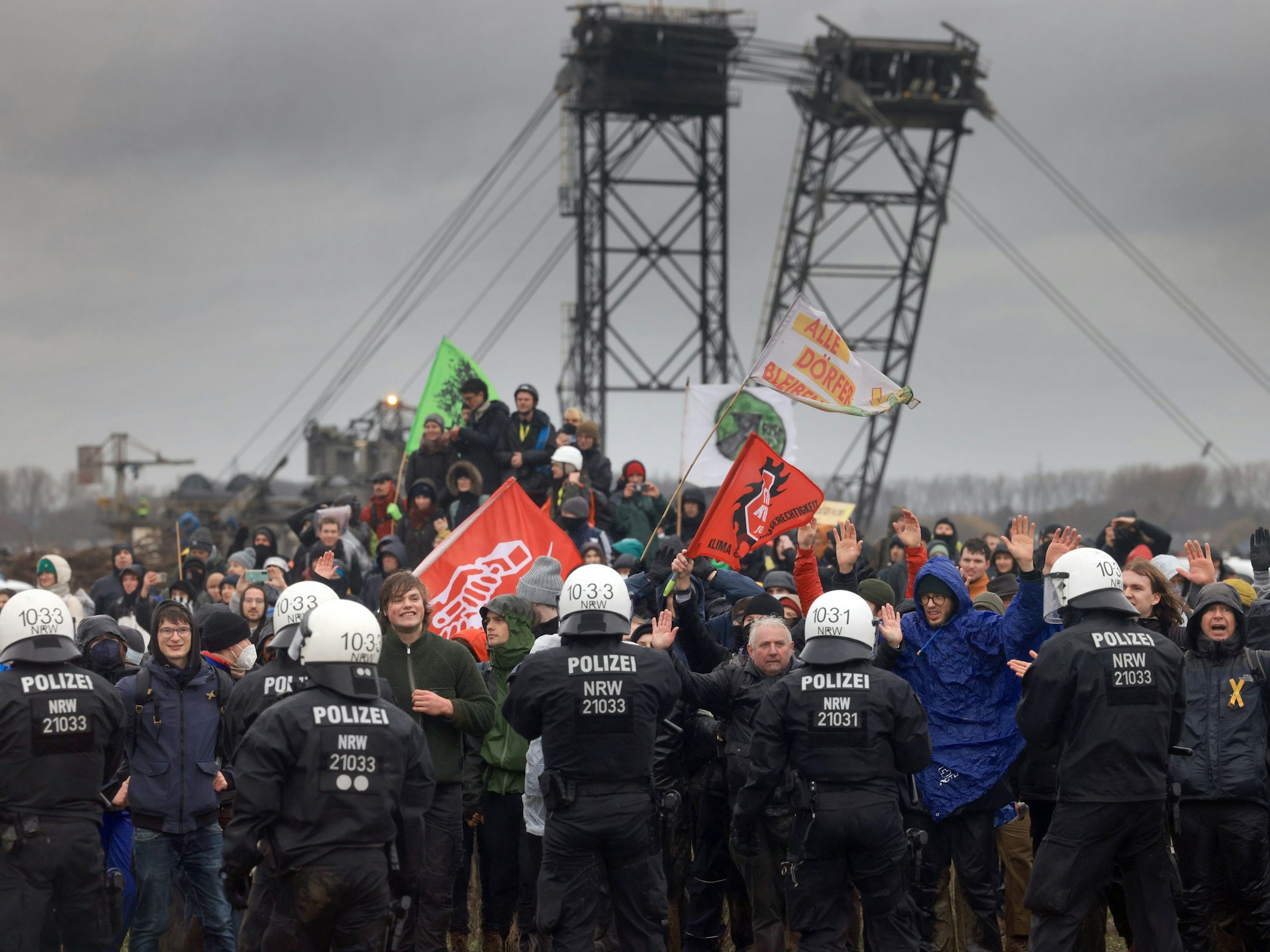 In Lützerath stehen sich am 14. Januar 2023 Mitglieder einer Einsatzhundertschaft der Polizei sowie Demonstrierende vor einem gigantischen Kohlebagger gegenüber.