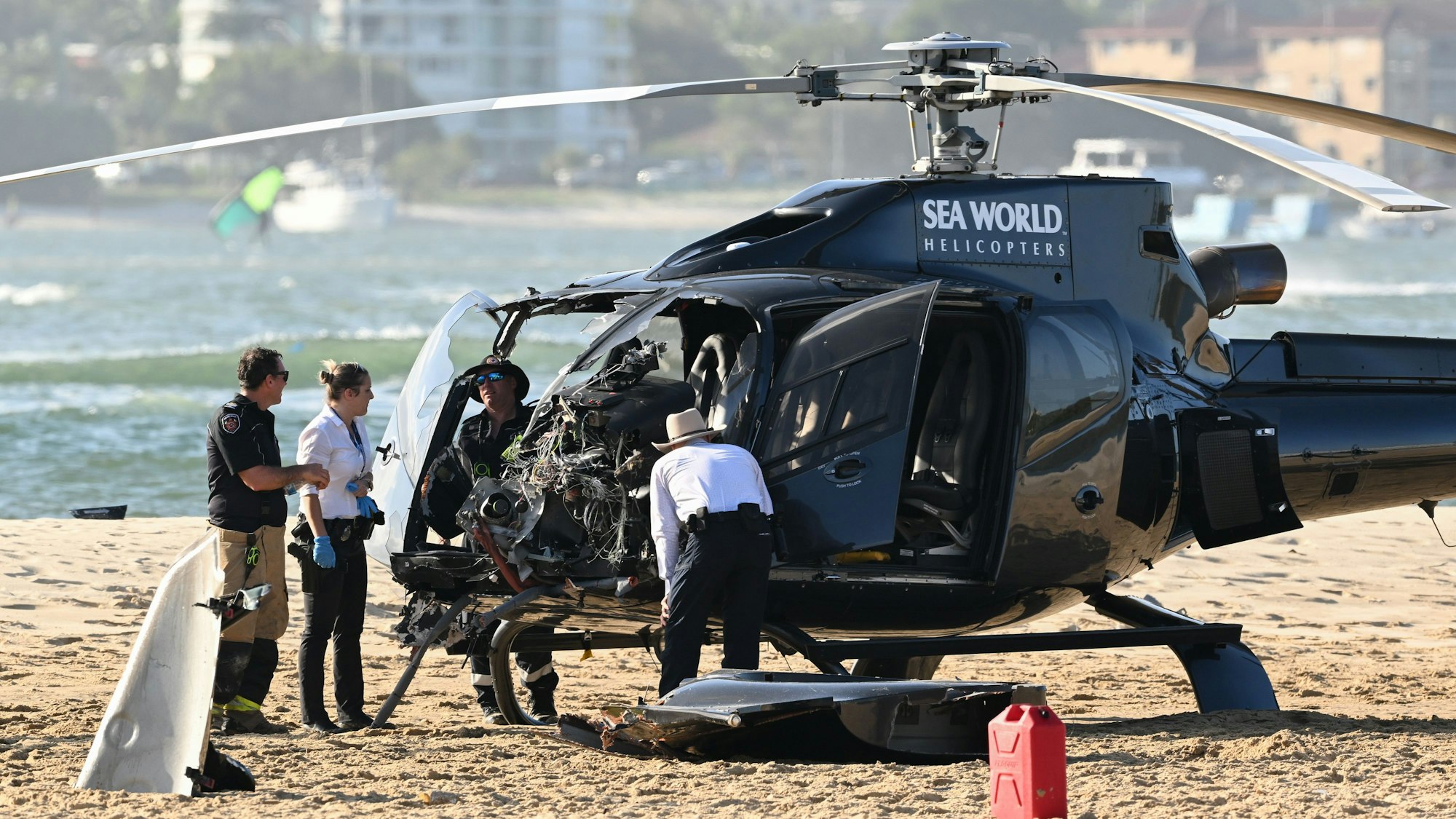 Mitarbeiter der Polizei, der Feuerwehr und des Rettungsdienstes, hier im Januar 2023, inspizieren einen Sea-World-Hubschrauber am Ort einer Hubschrauber-Kollision in der Nähe von Seaworld. An der australischen Gold Coast sind zwei Hubschrauber in der Luft kollidiert.
