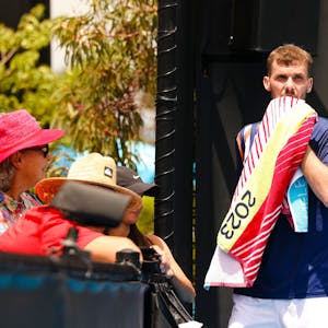 Tennisprofi Oscar Otte wischt sich mit einem Handtuch durchs Gesicht.