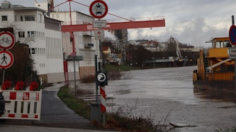 Blick auf den abgesperrten Leinpfad in Wesseling. Das Wasser des Rheins steht sehr hoch und überschwemmt den Weg teilweise.
