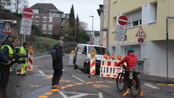 Ein Radfahrer und ein Fußgänger stehen vor der gesperrten Straße.