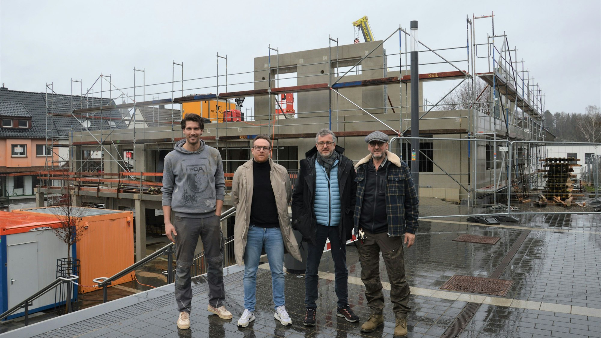 Vier Männer stehen vor der Baustelle eines neuen Hauses am Kaller Bahnhof.