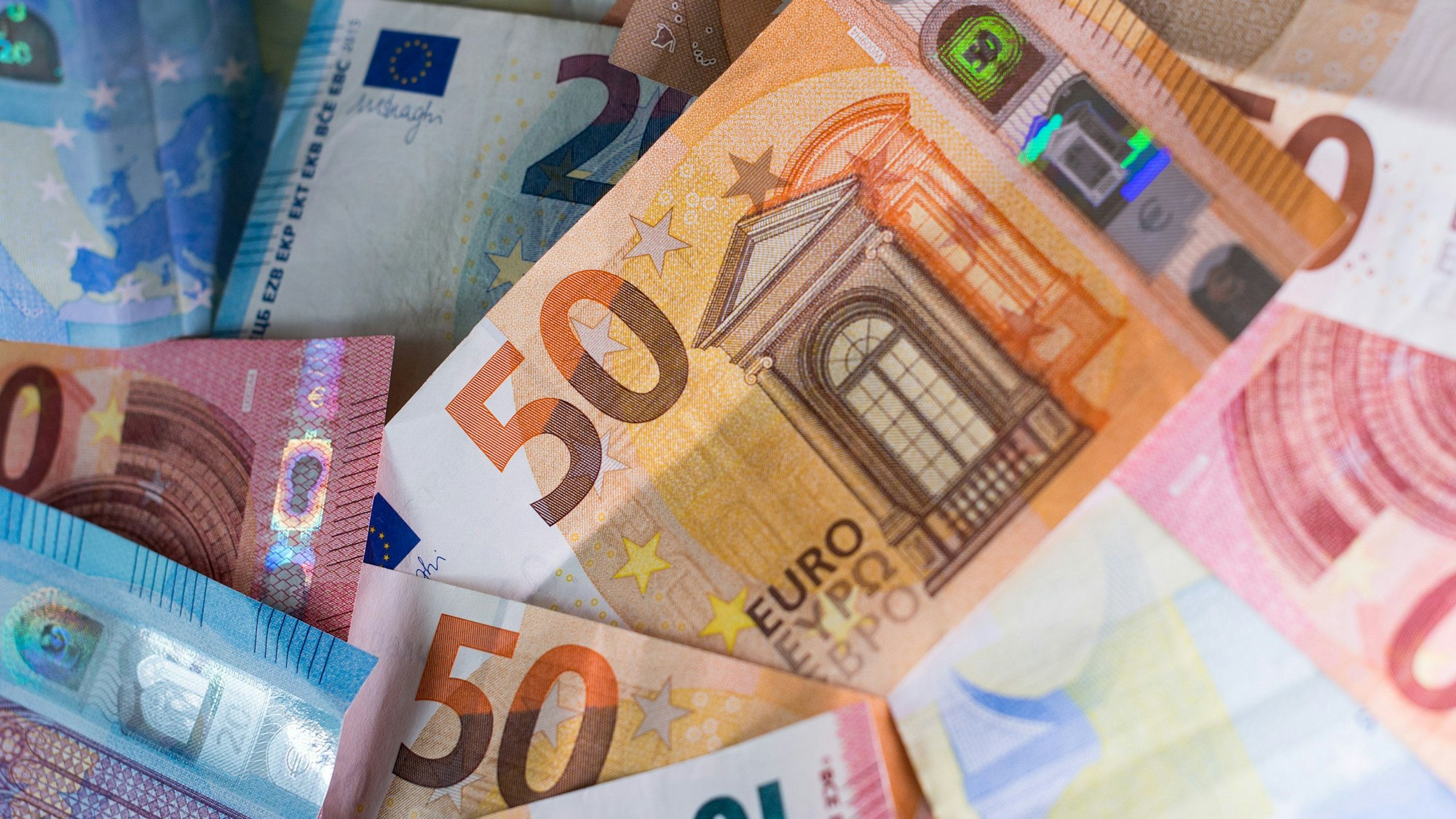 Zahlreiche Euro-Banknoten – 50er, 20er und 10er – liegen auf einem Tisch.