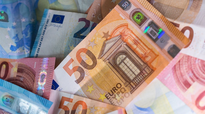 Zahlreiche Euro-Banknoten – 50er, 20er und 10er – liegen auf einem Tisch.