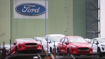 Neu gebaute Autos stehen auf Lastwagen vor dem Ford Werk.