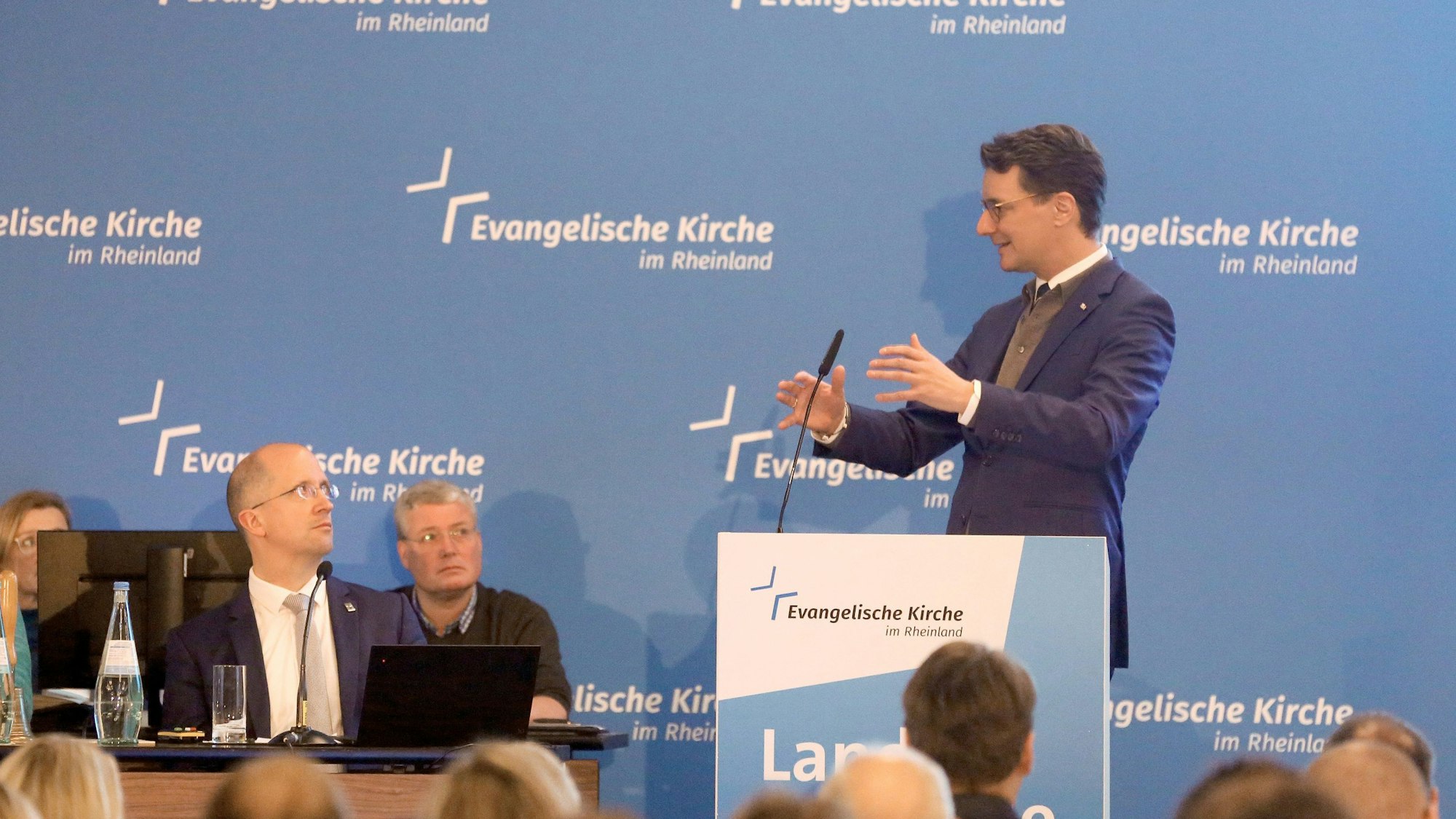 Der nordrhein-westfälische Ministerpräsident Hendrik Wüst (CDU) spricht während der Landessynode der Evangelischen Kirche im Rheinland zu den Teilnehmern, links sitzt Thorsten Latzel, Präses der Evangelischen Kirche im Rheinland.