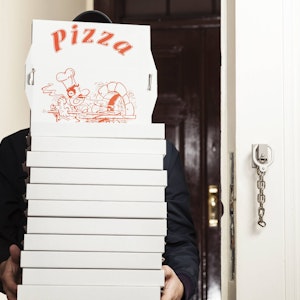 Ein Pizzabote hat einige Pizzakartons in den Händen.
