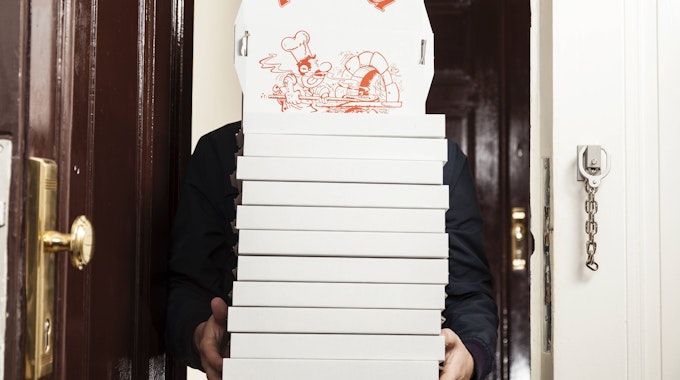 Ein Pizzabote hat einige Pizzakartons in den Händen.