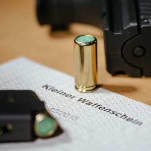 Ein kleiner Waffenschein liegt zwischen einer Schreckschuss-Pistole „Walther P22“, einem Magazin und einer Platzpatrone.