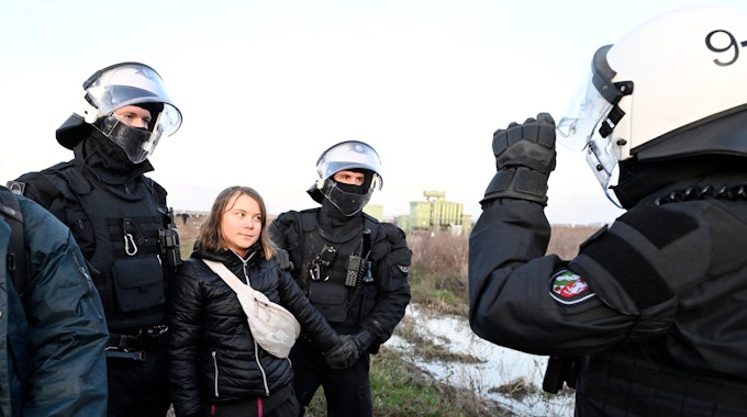 Polizisten haben die schwedische Klimaaktivistin Greta Thunberg (2.v.l.)&nbsp;aus einer Gruppe von Demonstranten und Aktivisten heraus und vom Rand des Braunkohlentagebaus Garzweiler II weggebracht und halten sie fest.