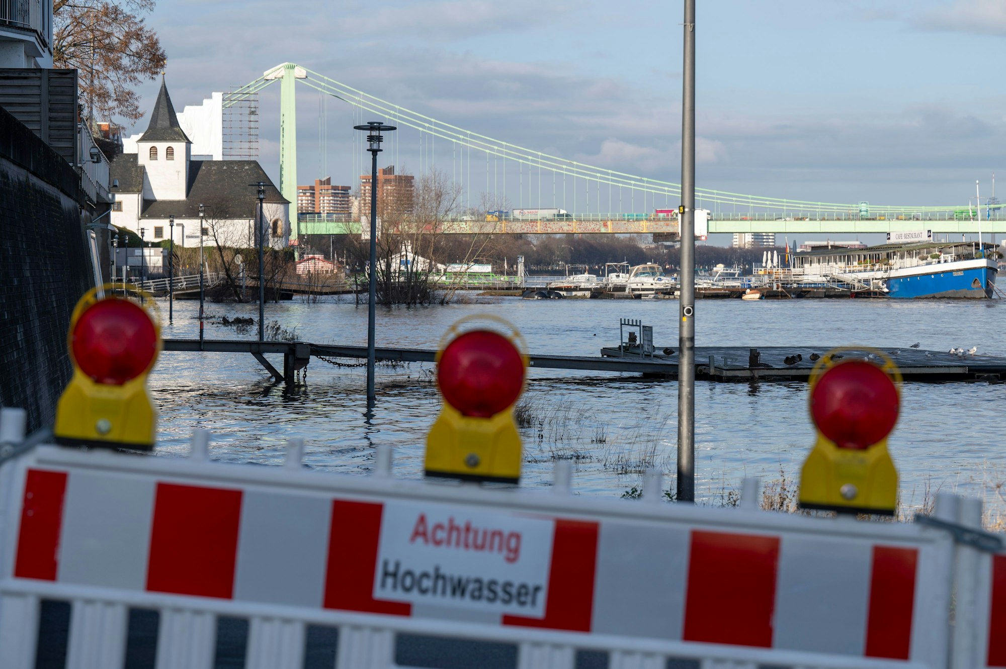 Rheinhochwasser in Rodenkirchen: Eine Absperrung steht am Ufer. Auf ihr steht "Achtung Hochwasser"