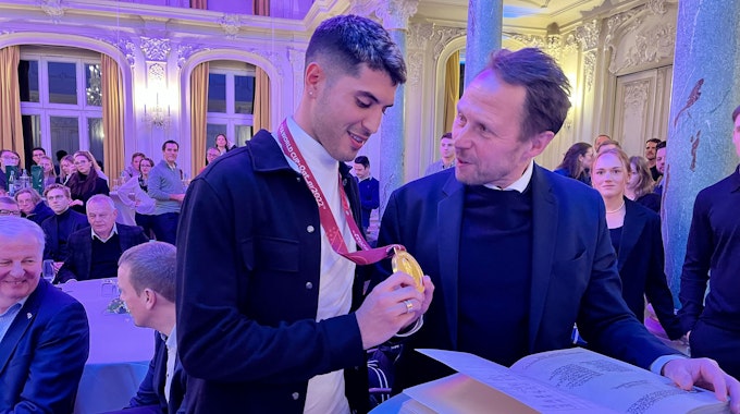Exequiel Palacios zeigt Uwe Richrath seine goldene WM-Medaille
