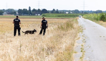 Polizisten und ein Hund suchen im August nach der Abgabe mehrerer Schüsse auf einem Feld bei Essig nach Spuren.