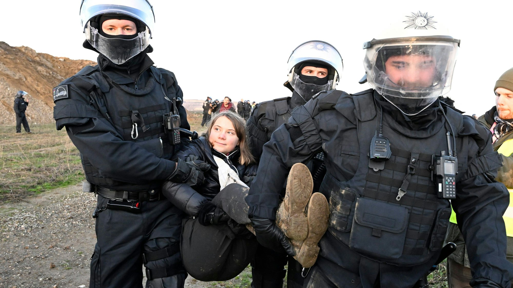 Polizisten tragen die schwedische Klimaaktivistin Greta Thunberg aus einer Gruppe von Demonstranten und Aktivisten heraus und vom Rand des Braunkohlentagebaus Garzweiler II weg.