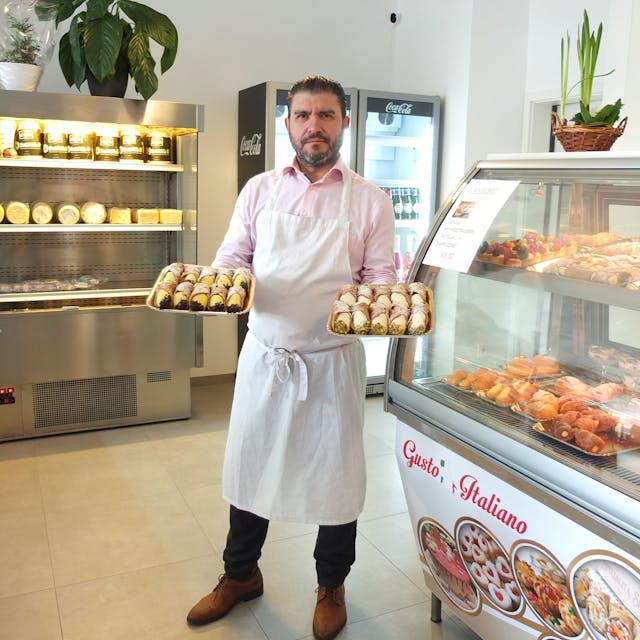 Francesco Bonfissuto mit süßen Spezialitäten in der Hand in seinem Geschäft.