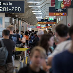 Zahlreiche Passagiere warten am Flughafen Köln/Bonn an der Sicherheitskontrolle. Es ist ein Schild mit Hinweisen zum Check-in zu sehen.