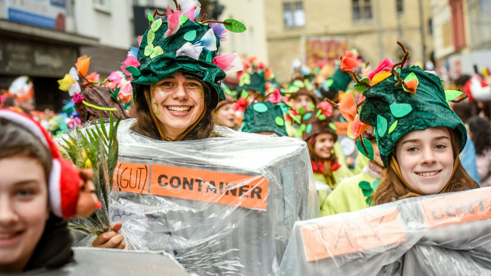 Teilnehmer der Schull- un Veedelszöch laufen über die Severinstraße. Die Schülerinnen sind mit Blumenhüten als Container verkleidet .